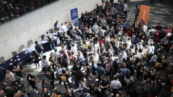a crowd of people gathering around a table at a conference