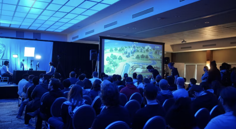 a crowd at a conference looking at a big screen