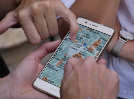 a finger pointing to a map on a mobile device
