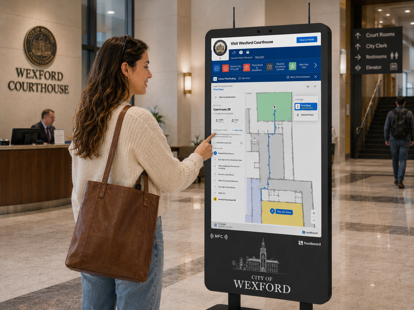 A visitor taps a HootBoard wayfinding kiosk in a courthouse lobby, following step-by-step directions to Courtroom 3B.